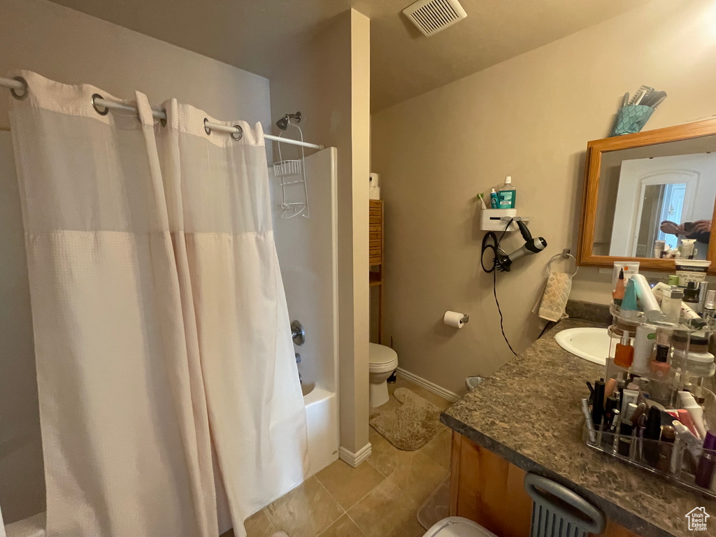 Bathroom featuring tile patterned floors, visible vents, shower / bath combo with shower curtain, toilet, and vanity
