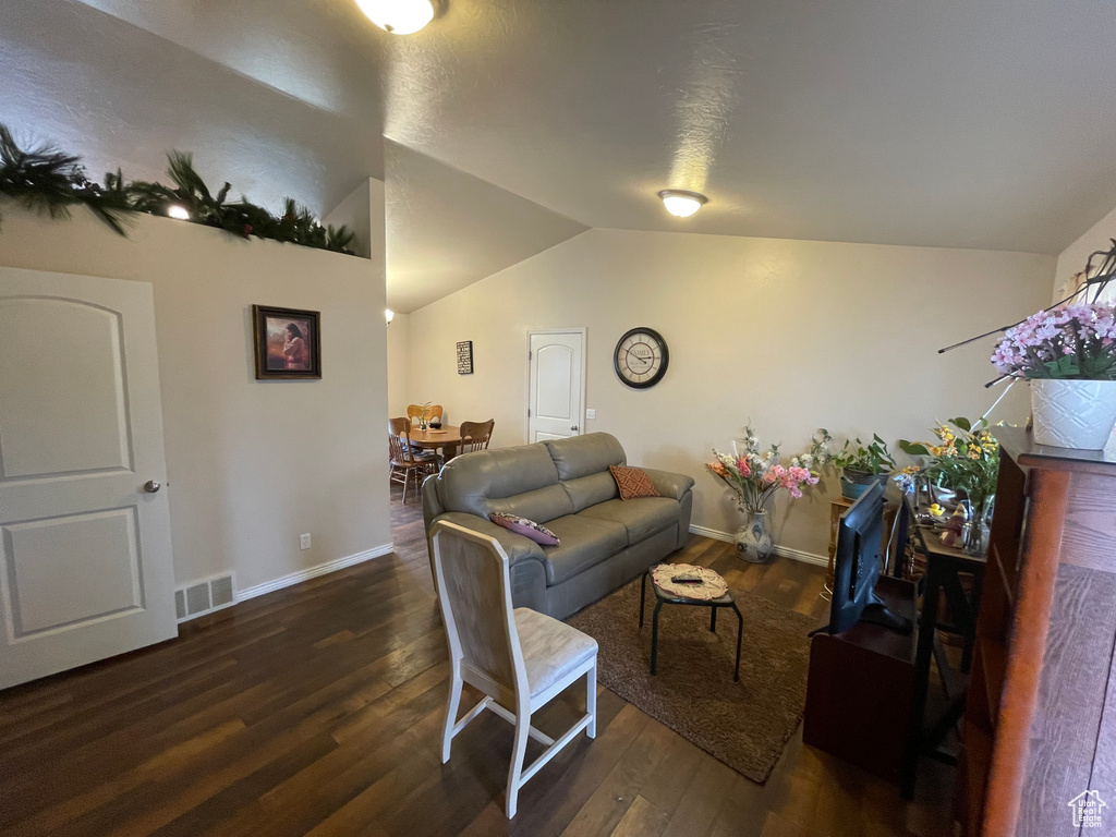 Living area featuring baseboards, lofted ceiling, visible vents, and wood finished floors