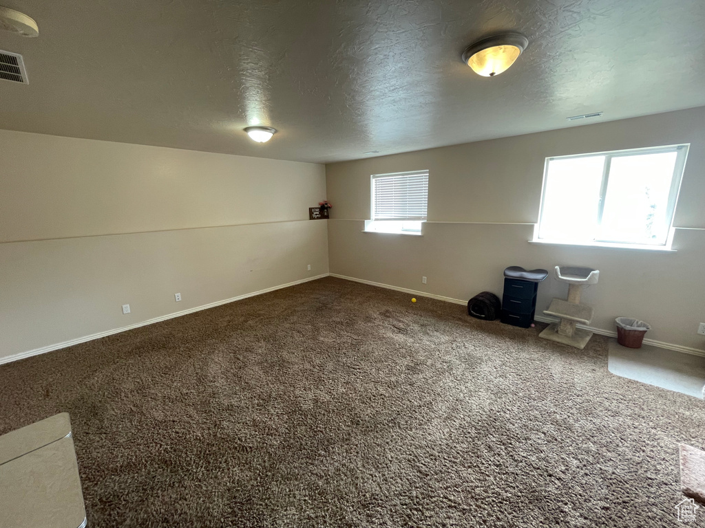 Interior space featuring carpet flooring, baseboards, visible vents, and a textured ceiling