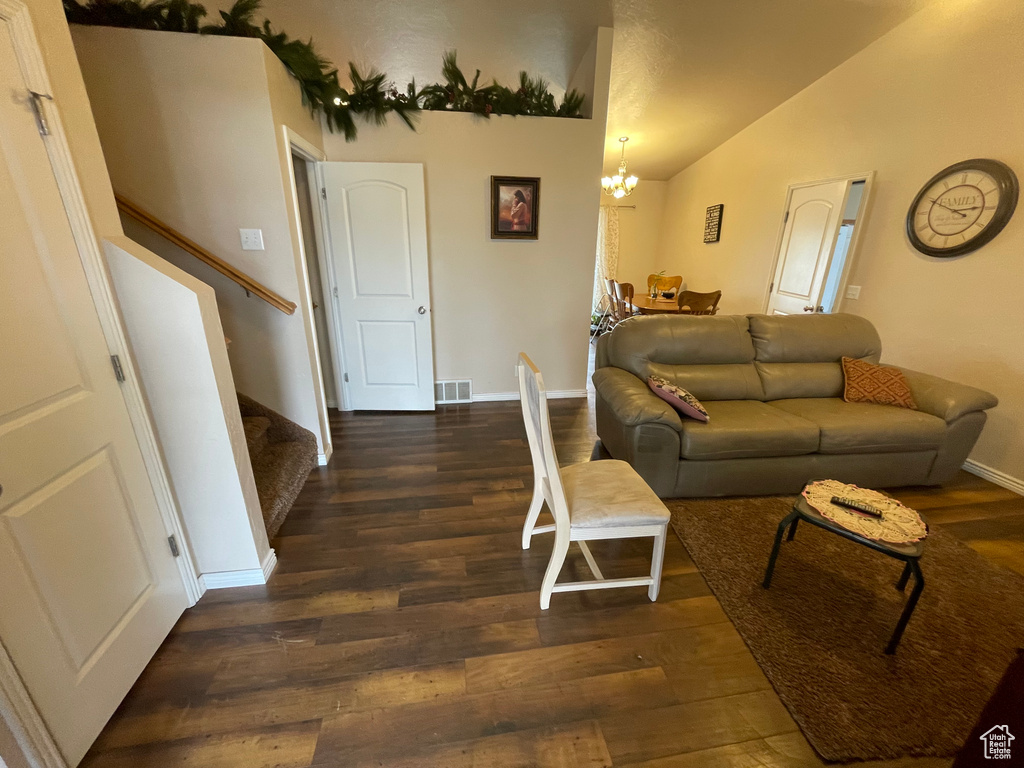Living area featuring visible vents, wood finished floors, stairway, an inviting chandelier, and vaulted ceiling