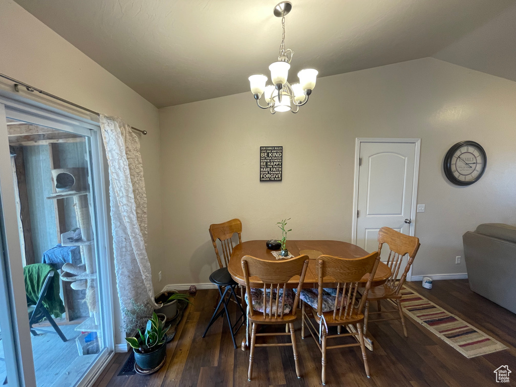Dining area featuring lofted ceiling, wood finished floors, baseboards, and a chandelier