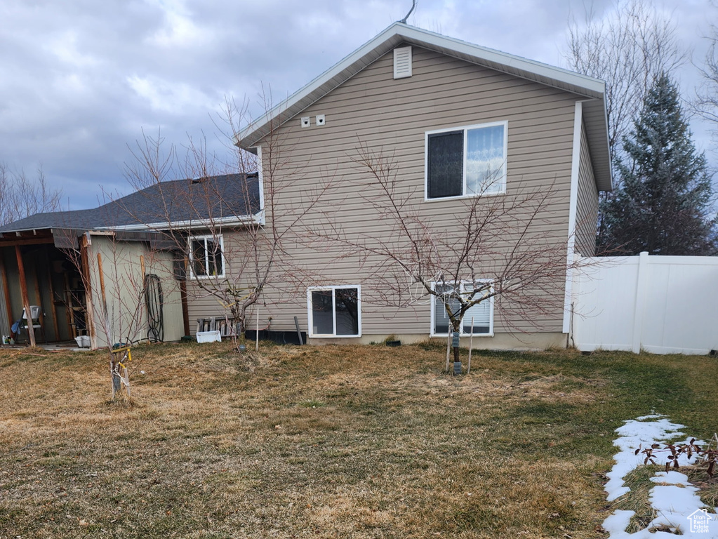 Rear view of property with a yard and fence
