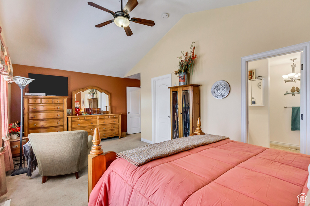 Bedroom featuring high vaulted ceiling, ceiling fan with notable chandelier, ensuite bathroom, and light carpet