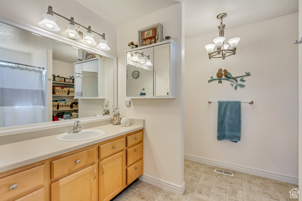 Full bath with a notable chandelier, visible vents, vanity, and baseboards