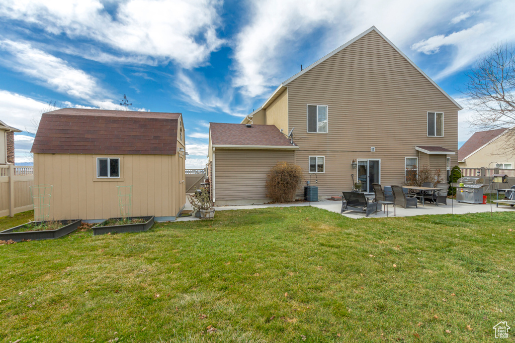 Back of property featuring a vegetable garden, an outdoor structure, a storage shed, a patio area, and a lawn
