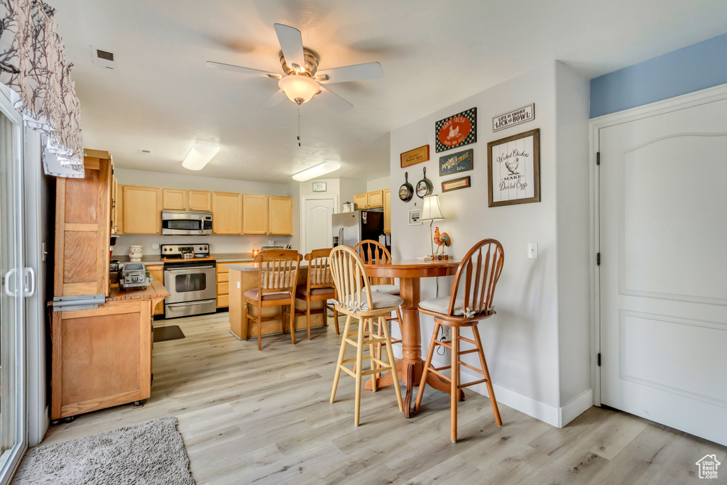 Kitchen featuring a kitchen breakfast bar, light wood-style floors, light brown cabinetry, and stainless steel appliances