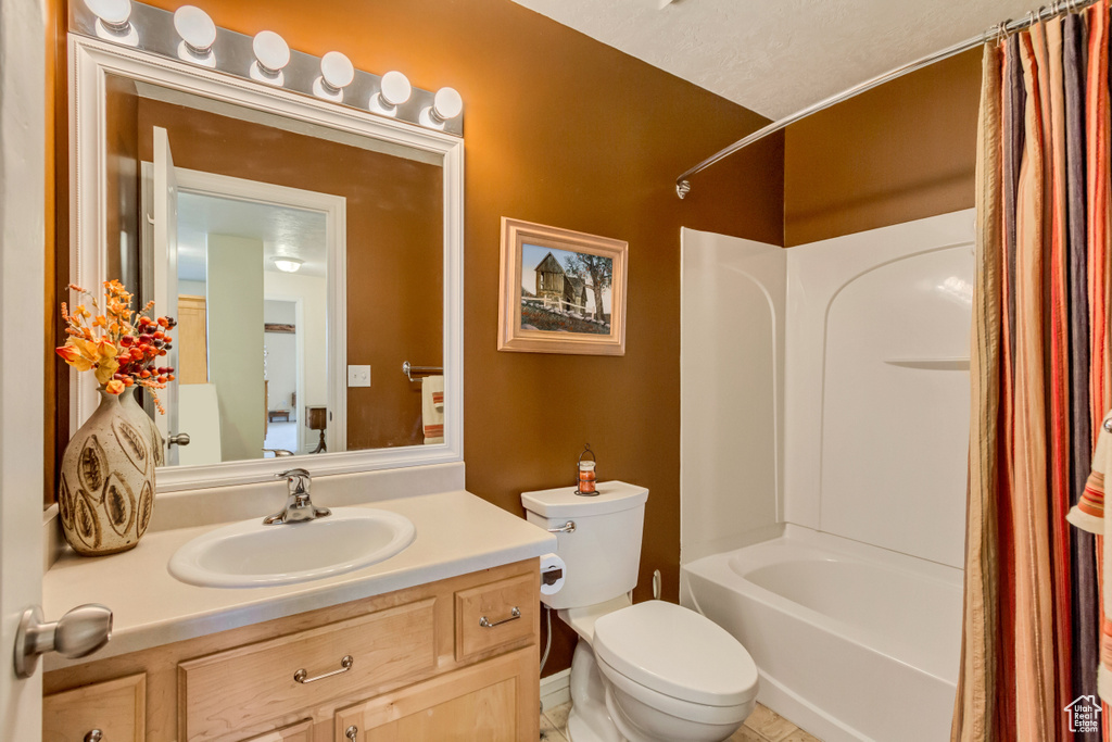 Bathroom with shower / bath combo with shower curtain, toilet, and vanity