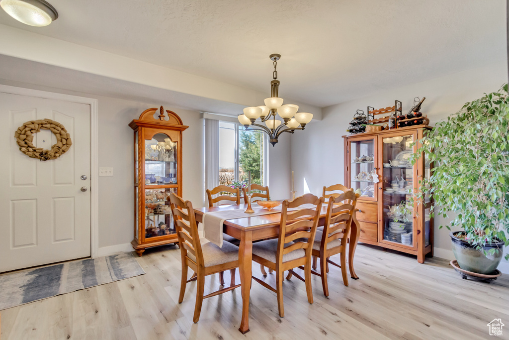Dining area featuring light wood-type flooring, baseboards, and an inviting chandelier