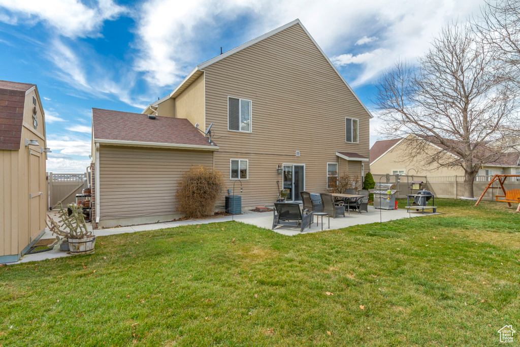 Back of house featuring a patio area, a lawn, central AC, and a fenced backyard