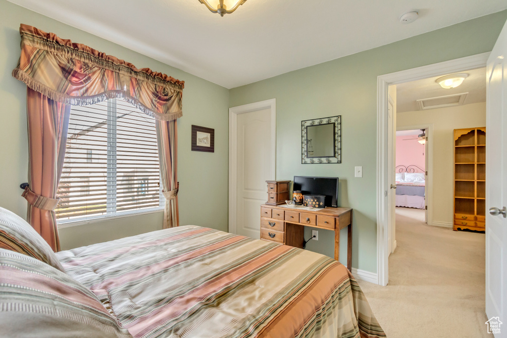 Bedroom with baseboards, light colored carpet, and attic access