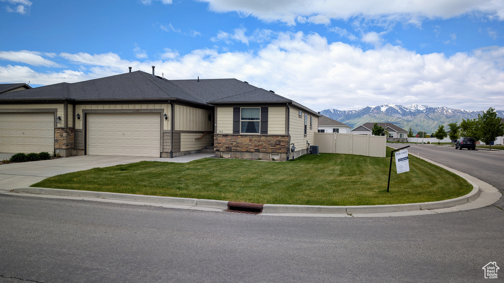 View of front of home with a mountain view, driveway, an attached garage, and stone siding