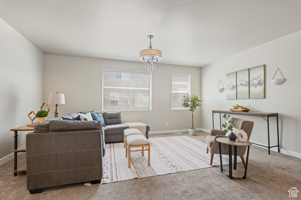 Living area featuring an inviting chandelier, baseboards, and carpet flooring