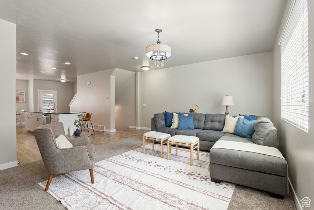 Living area featuring baseboards, light wood finished floors, recessed lighting, and a notable chandelier