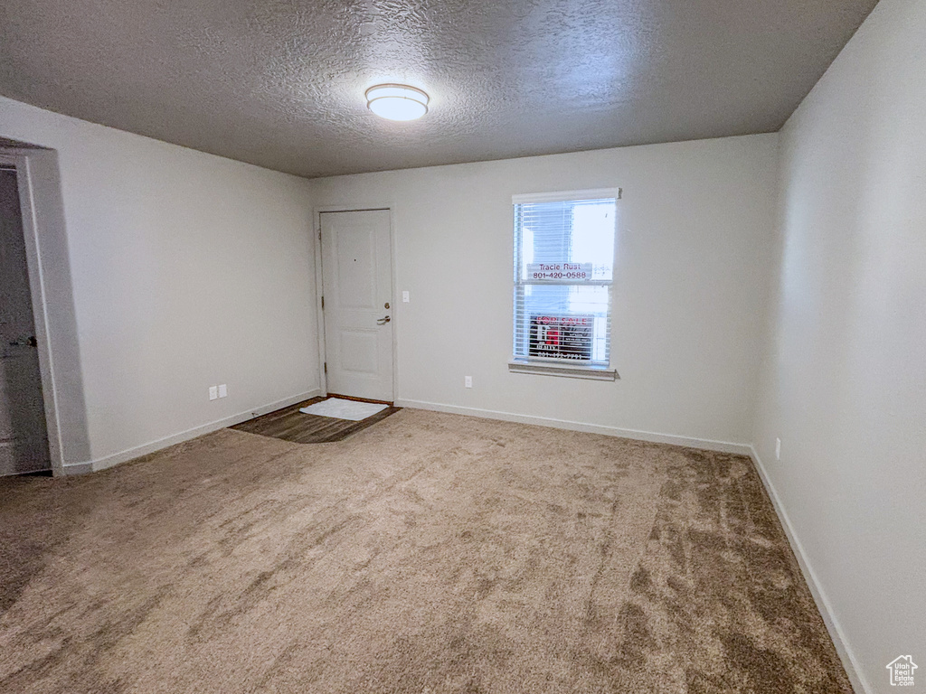 Carpeted empty room featuring baseboards and a textured ceiling