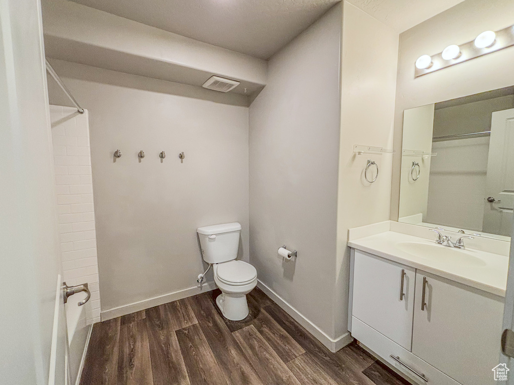 Full bath featuring toilet, wood finished floors, visible vents, and baseboards
