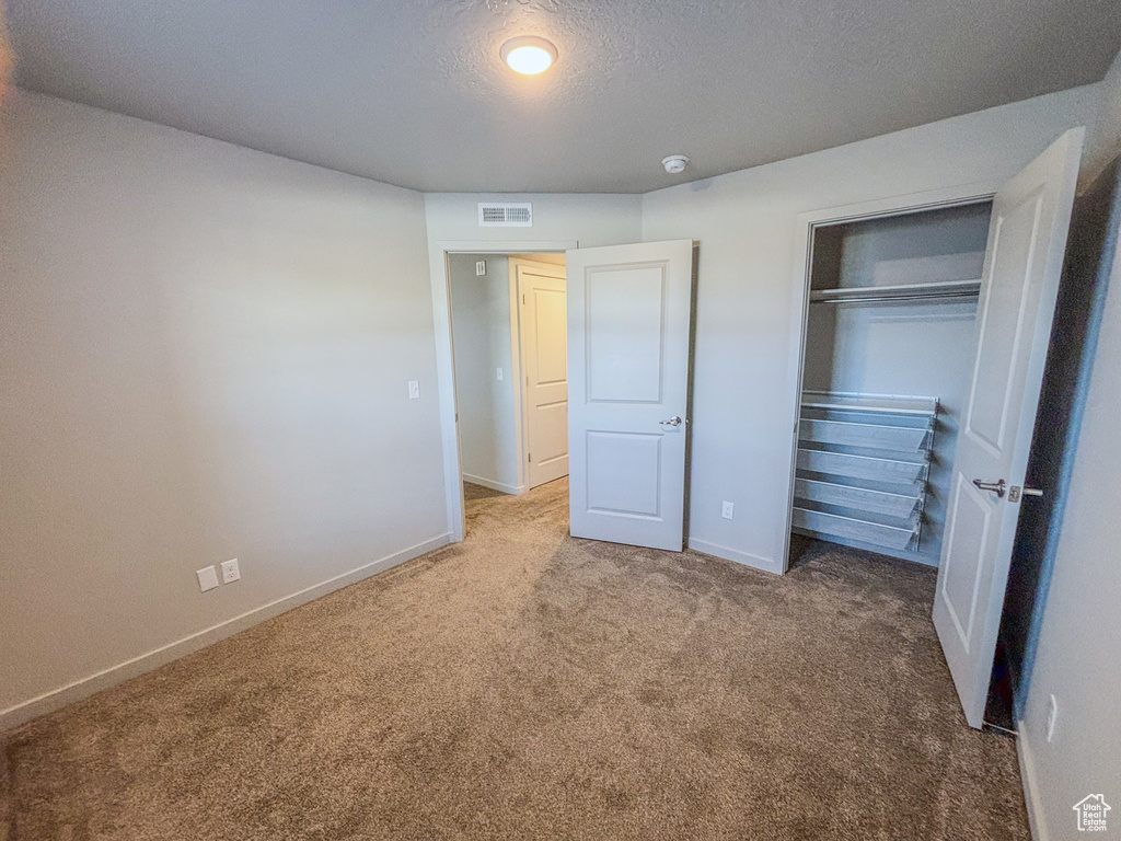 Unfurnished bedroom featuring carpet, visible vents, baseboards, a closet, and a textured ceiling
