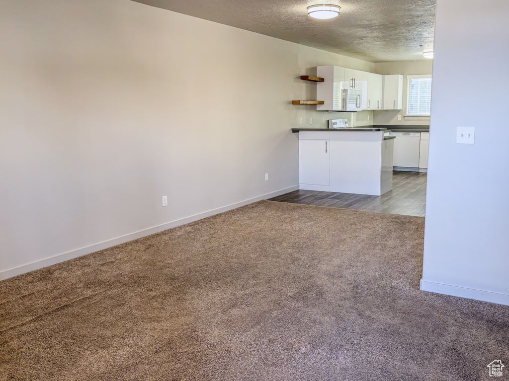 Interior space with dark countertops, carpet floors, white cabinets, white appliances, and open shelves