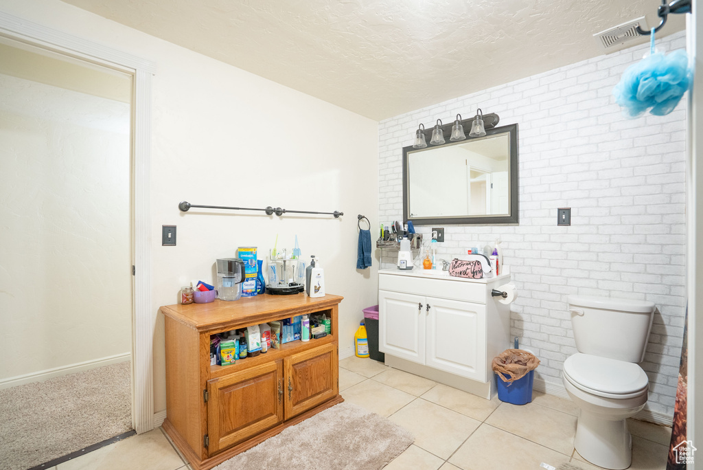 Bathroom featuring vanity, visible vents, brick wall, a textured ceiling, and toilet