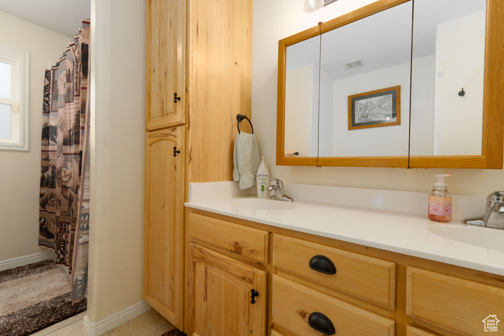 Bathroom featuring double vanity, baseboards, visible vents, and a sink