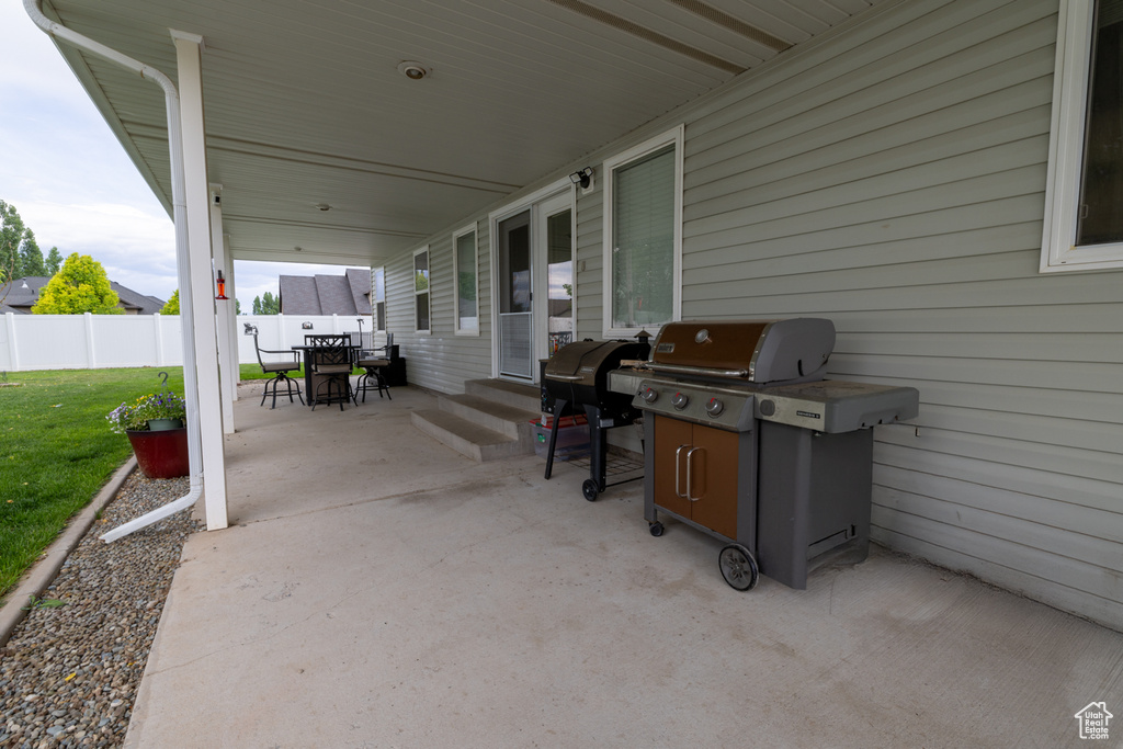 View of patio with outdoor dining area, a grill, and entry steps