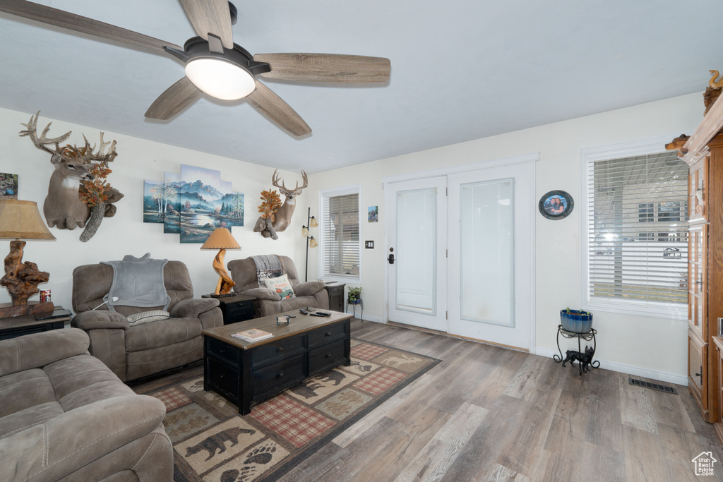 Living room featuring ceiling fan, wood finished floors, visible vents, and baseboards