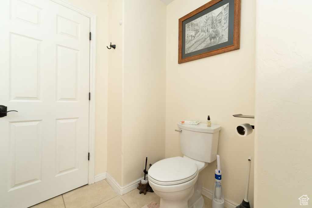 Bathroom featuring tile patterned flooring, toilet, and baseboards