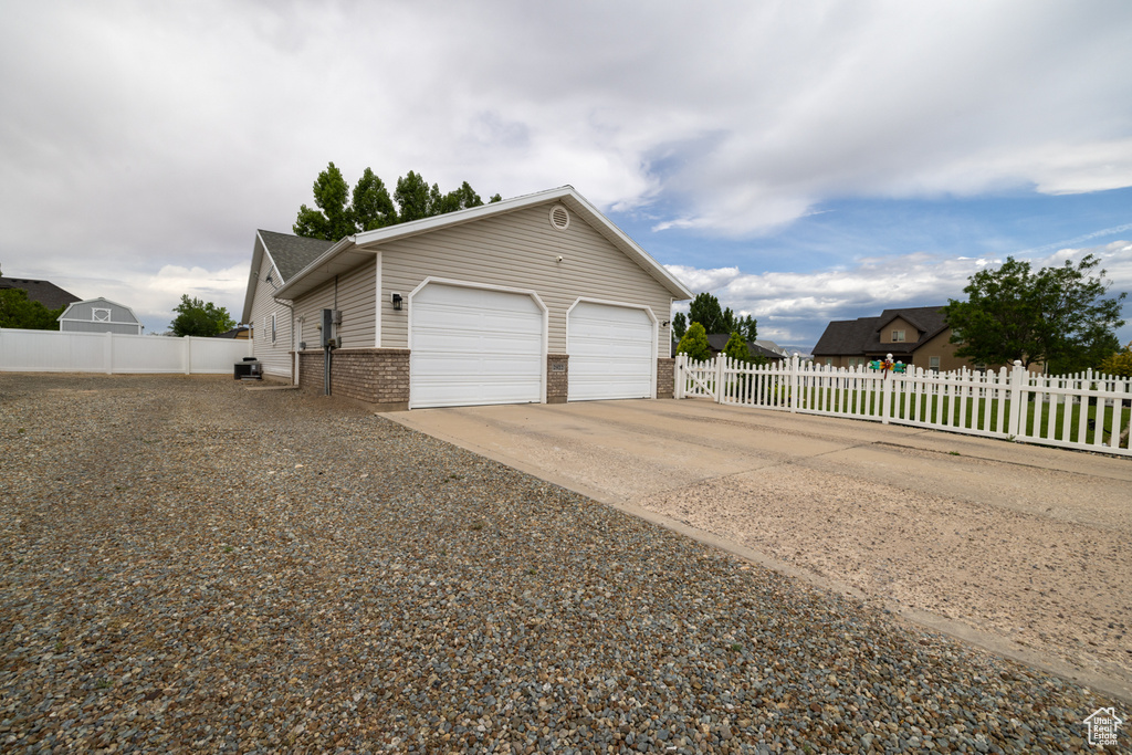 View of side of home with brick siding, concrete driveway, an attached garage, and cooling unit