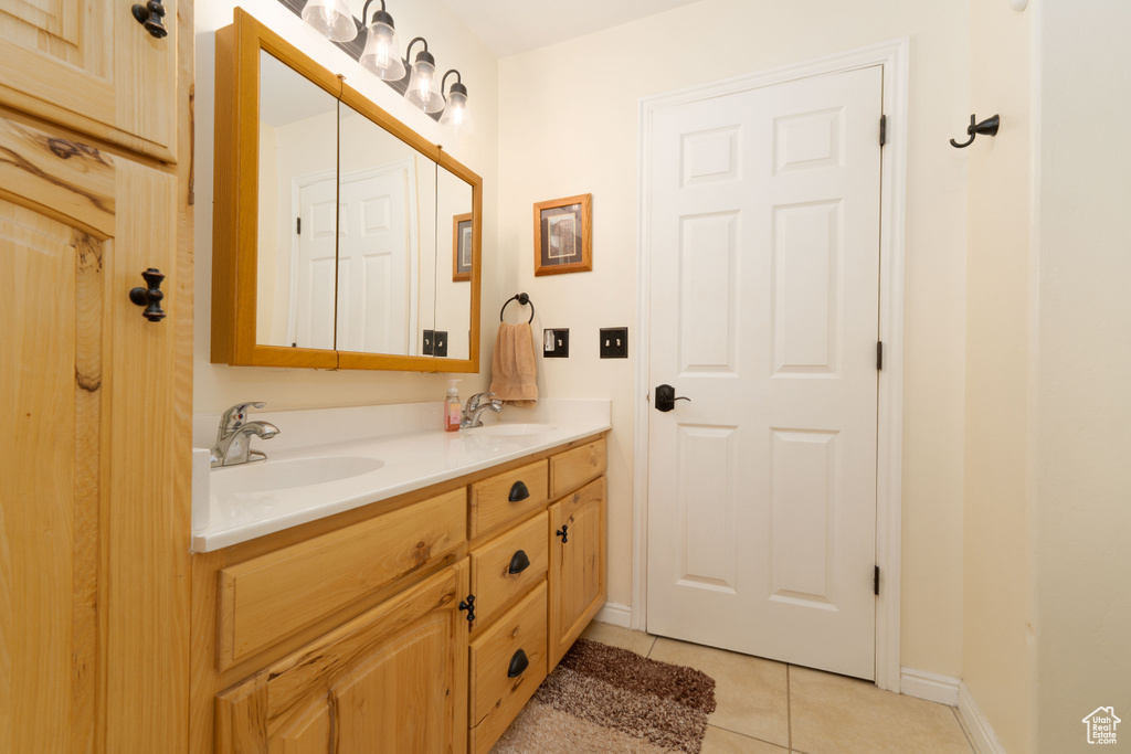 Full bath with a sink, baseboards, double vanity, and tile patterned flooring
