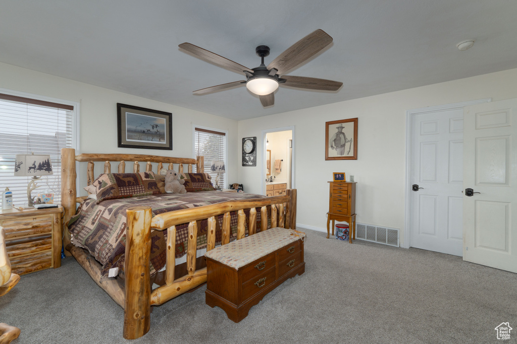 Carpeted bedroom featuring visible vents, baseboards, ceiling fan, and ensuite bathroom