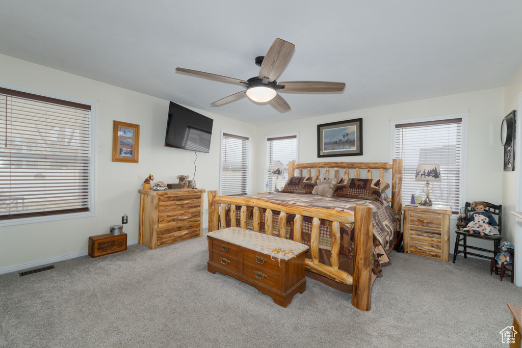 Bedroom with baseboards, light colored carpet, visible vents, and ceiling fan
