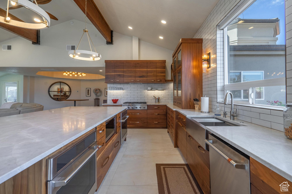 Kitchen featuring visible vents, lofted ceiling with beams, decorative backsplash, appliances with stainless steel finishes, and brown cabinetry