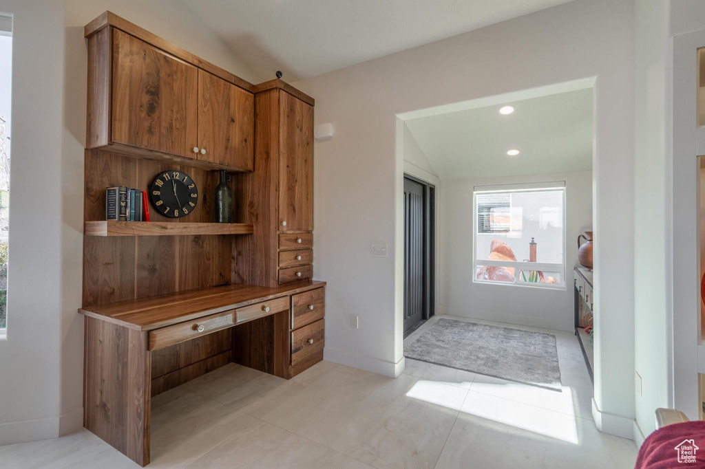 Interior space with recessed lighting, brown cabinets, baseboards, and vaulted ceiling