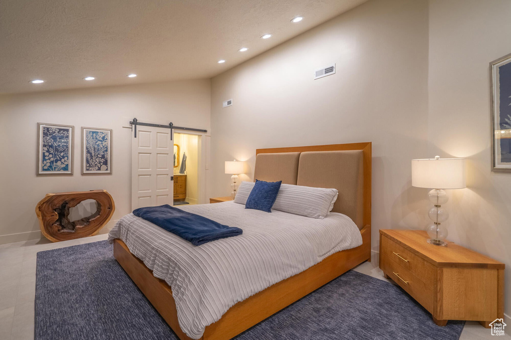 Bedroom featuring recessed lighting, a barn door, lofted ceiling, and visible vents