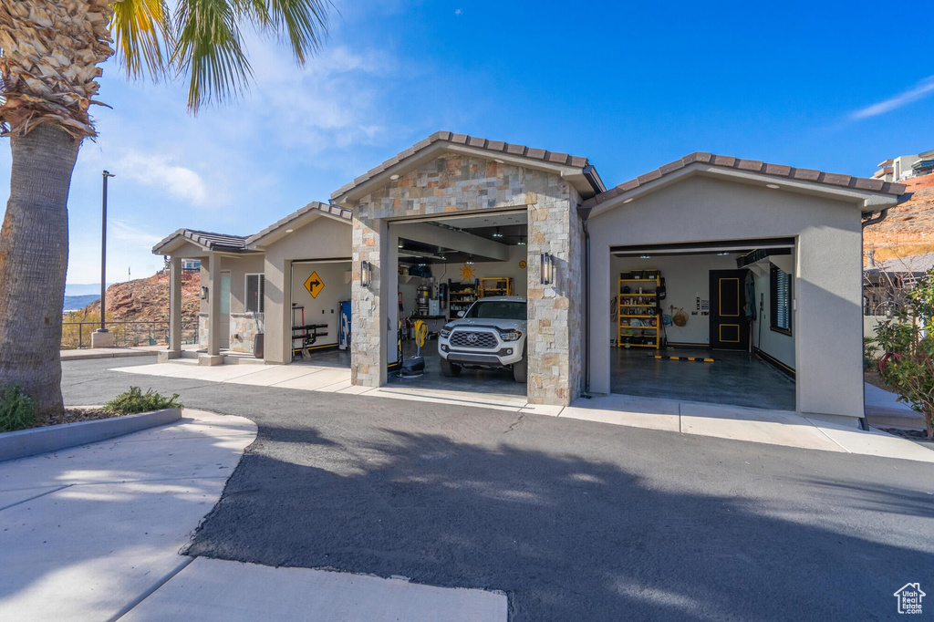 View of front of house with stucco siding, stone siding, and a garage