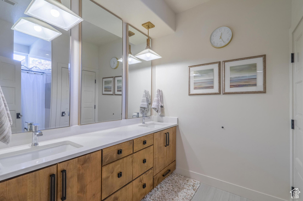 Bathroom featuring double vanity, visible vents, baseboards, and a sink