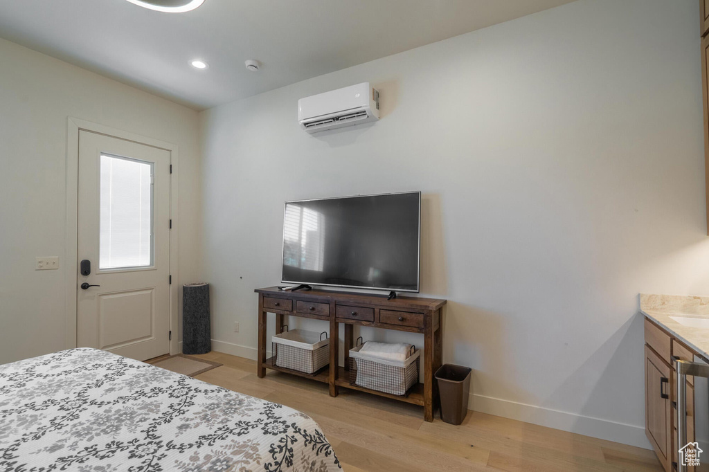 Bedroom featuring light wood finished floors, recessed lighting, a wall mounted AC, and baseboards