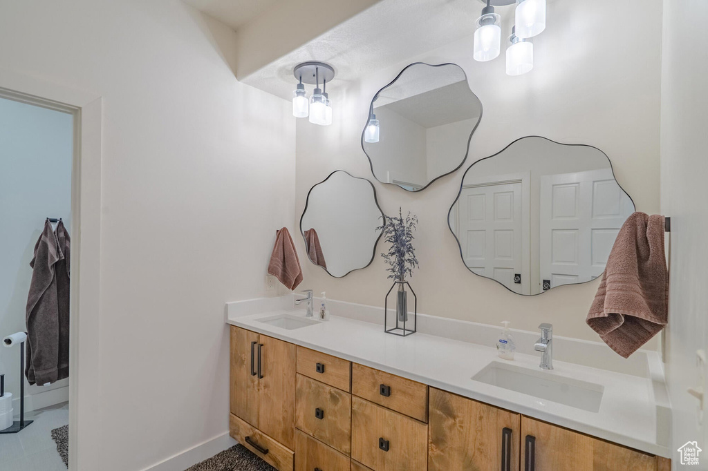 Full bathroom with double vanity, baseboards, and a sink