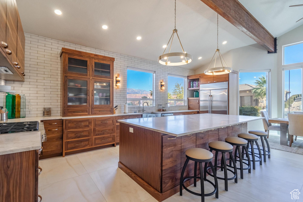 Kitchen featuring built in refrigerator, lofted ceiling with beams, a sink, brown cabinetry, and decorative backsplash