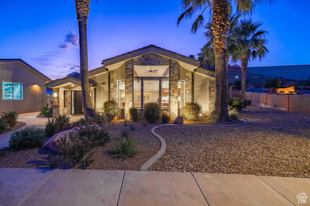 Mid-century modern home featuring stone siding and fence