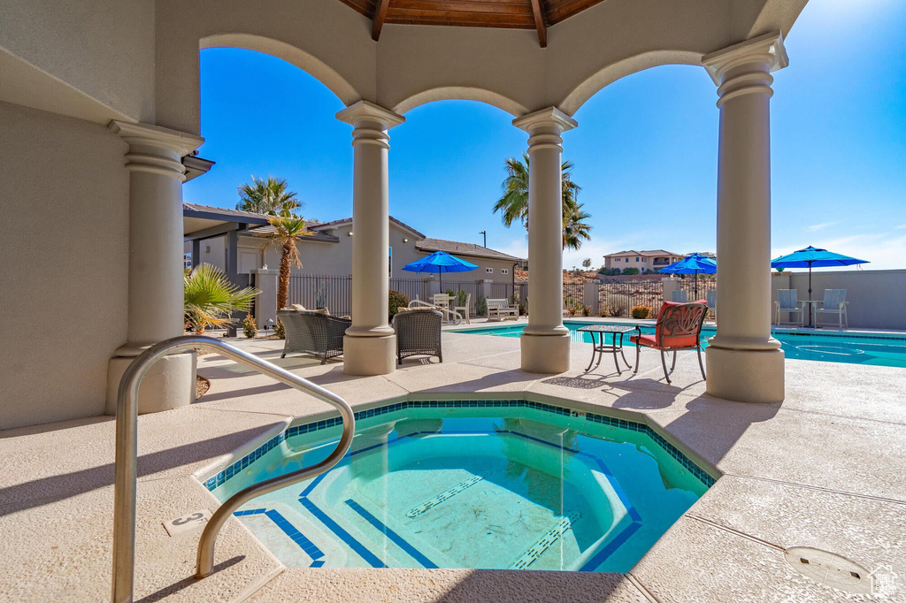 Pool with a community hot tub, a patio area, and fence