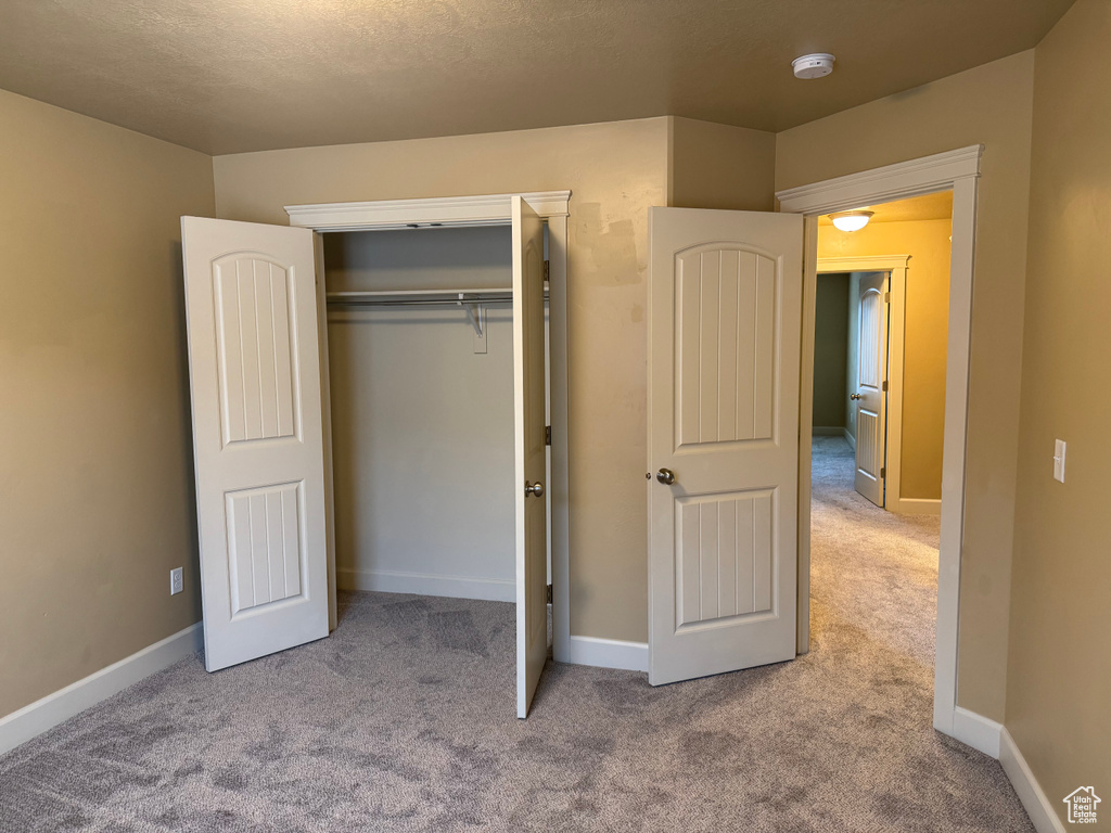 Unfurnished bedroom featuring baseboards, a closet, and carpet floors