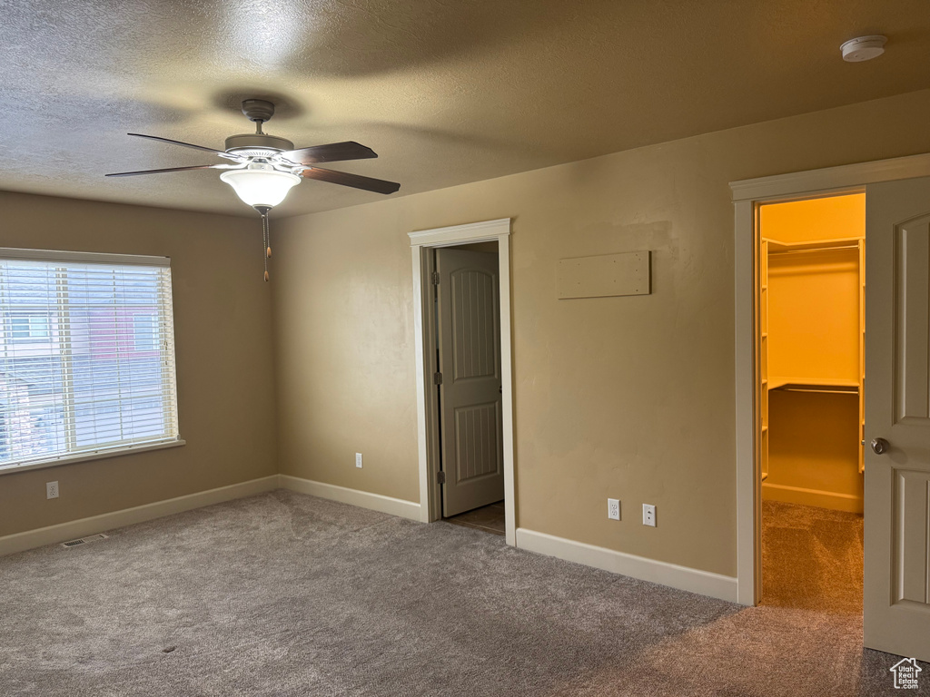 Unfurnished bedroom featuring baseboards, visible vents, carpet, and a walk in closet