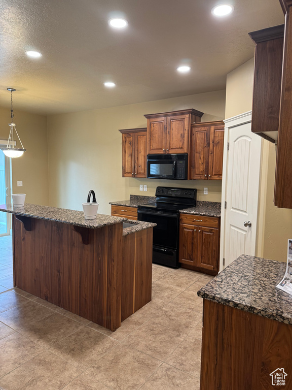 Kitchen featuring recessed lighting, a center island, decorative light fixtures, a breakfast bar, and black appliances