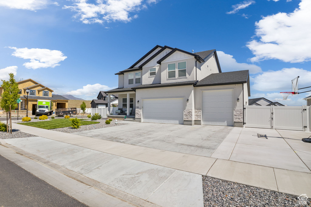 View of front facade featuring a gate, stone siding, fence, and stucco siding