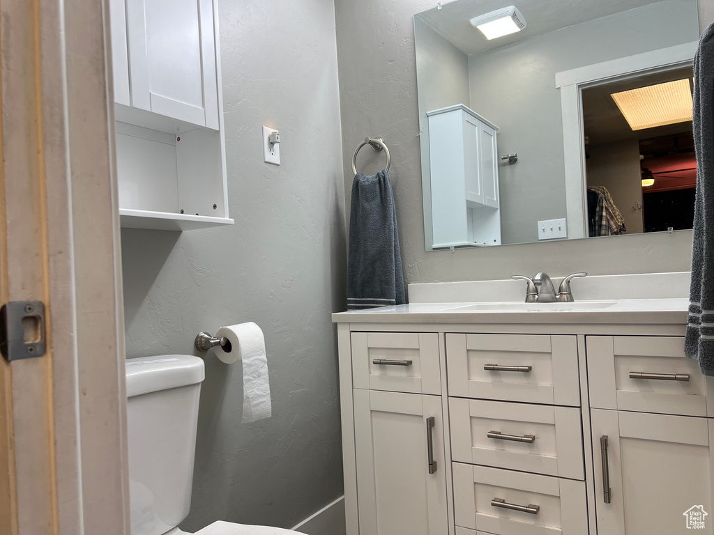 Bathroom with toilet, vanity, and a textured wall