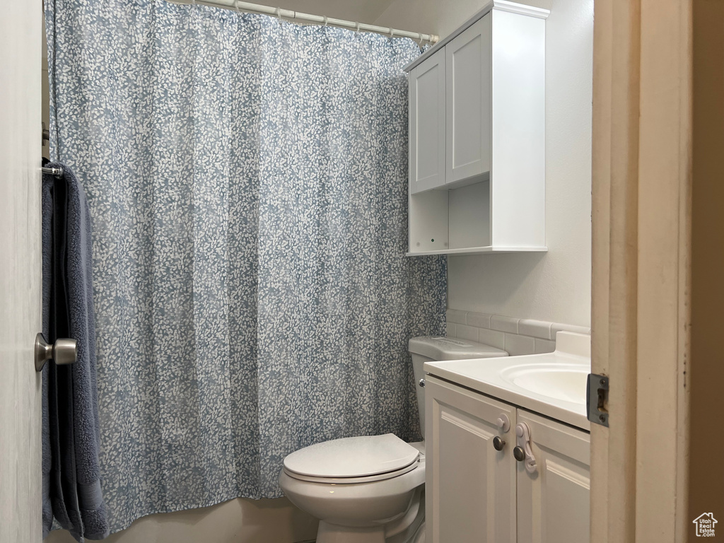 Full bath with toilet, vanity, and a shower with curtain