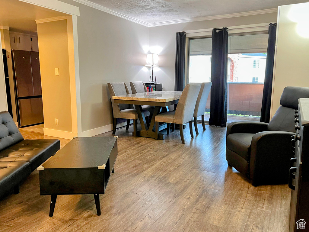 Dining room featuring light wood-type flooring, crown molding, and baseboards