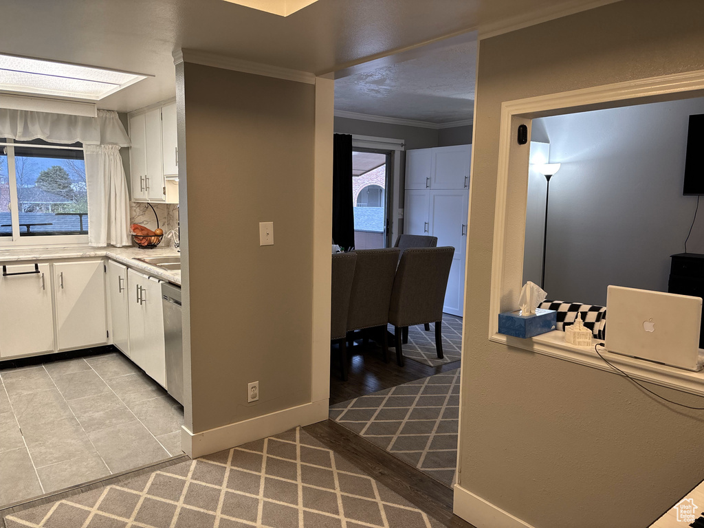 Kitchen featuring dishwasher, white cabinets, crown molding, and decorative backsplash