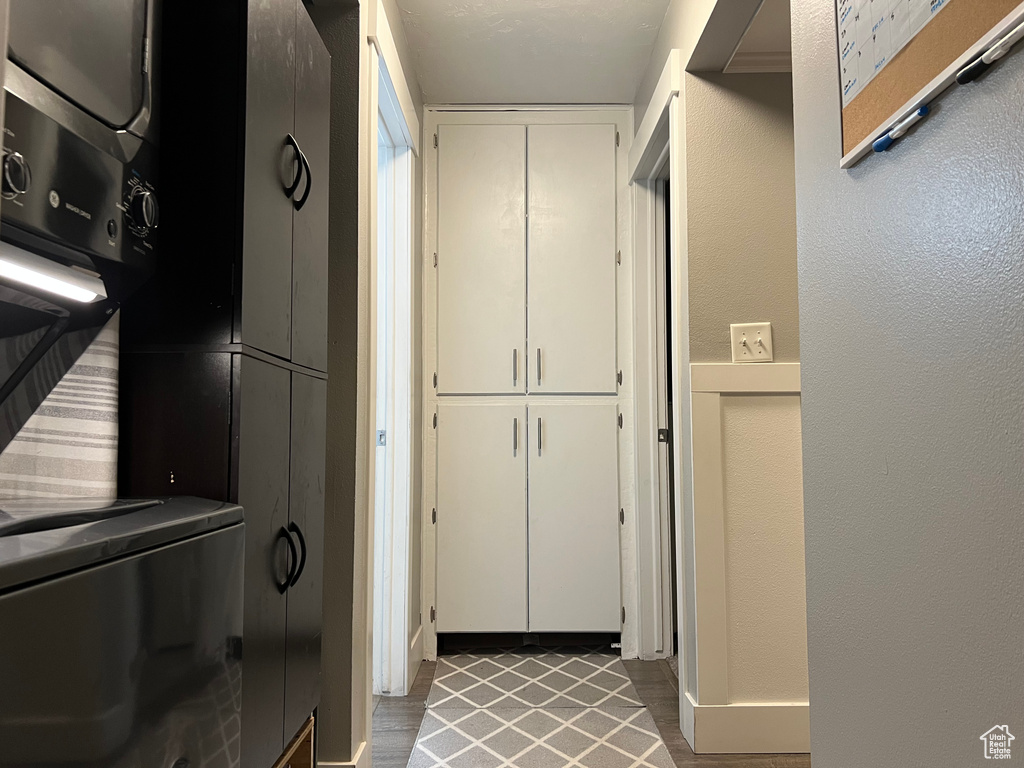 Clothes washing area with stacked washer and dryer, laundry area, and a textured wall