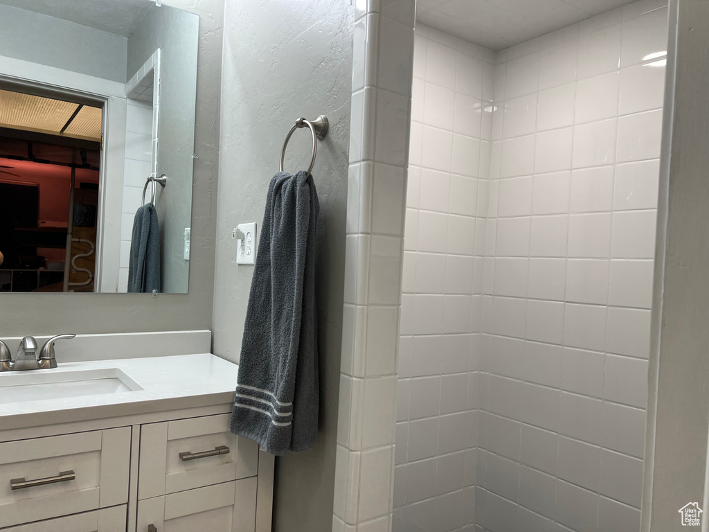 Bathroom featuring vanity, a textured wall, and tiled shower
